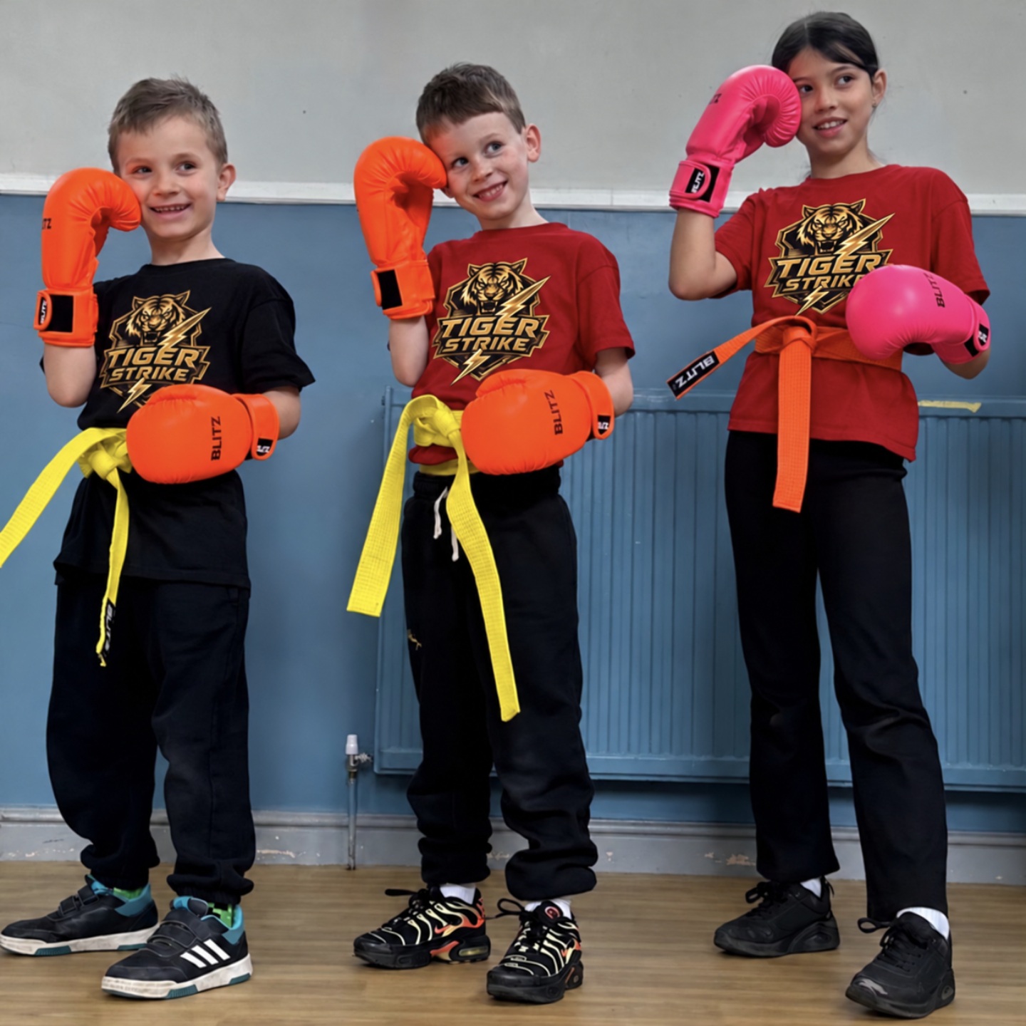 Three Tiger Strike students posing with boxing gloves